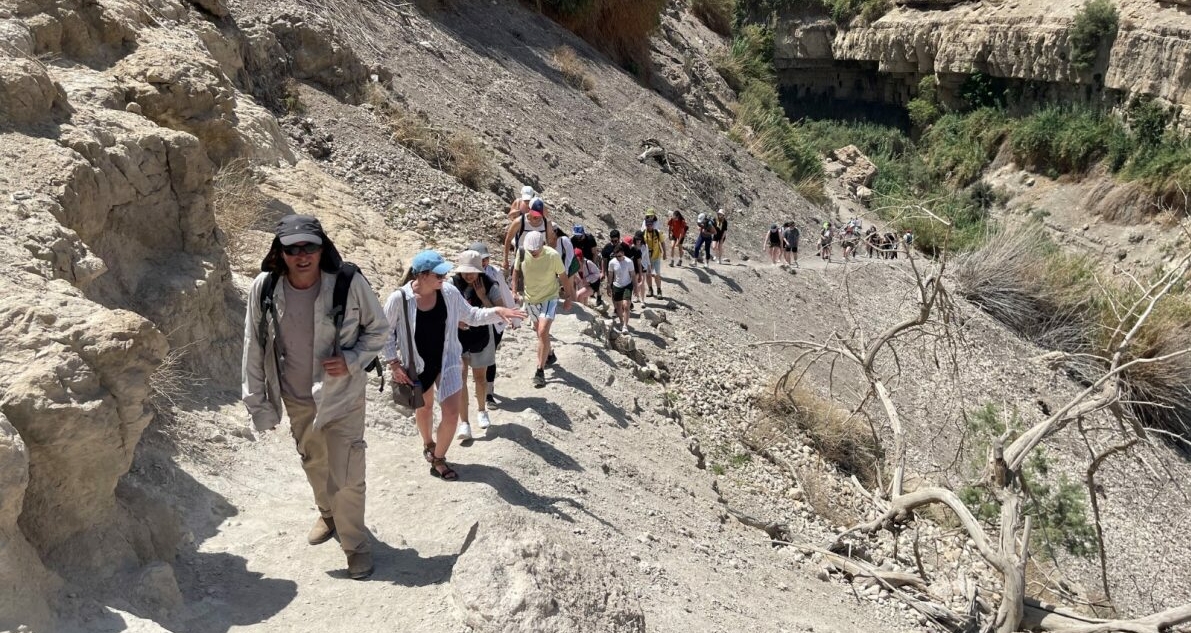 Un grand groupe d'adultes randonnant sur le sentier d'une montagne sèche.