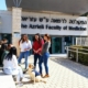 Un groupe d'étudiants et un chien d'assistance sont assis et discutent devant un bâtiment.