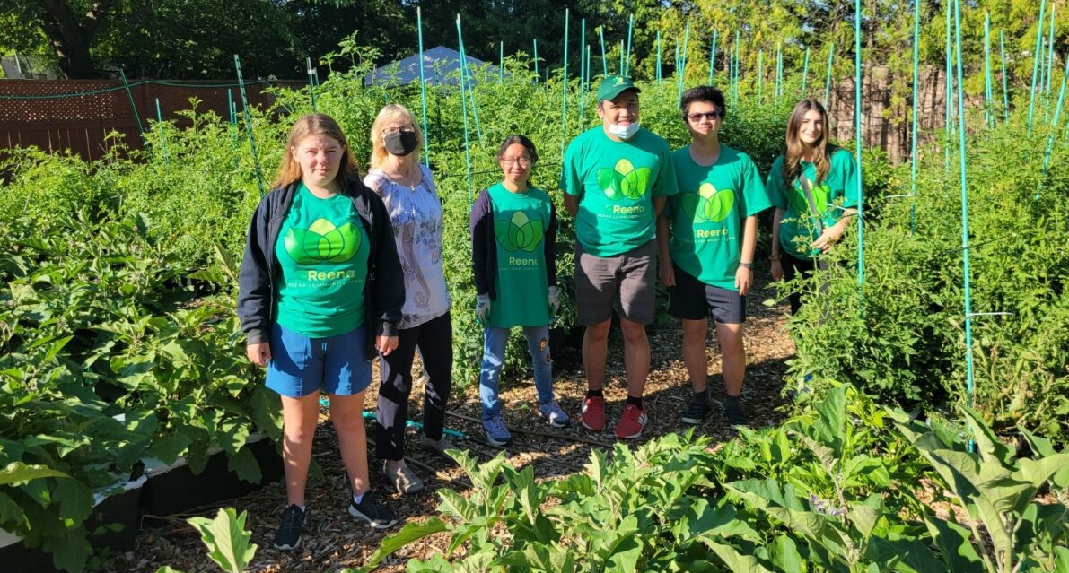 Six personnes debout dans un jardin très vert, portant des t-shirts verts