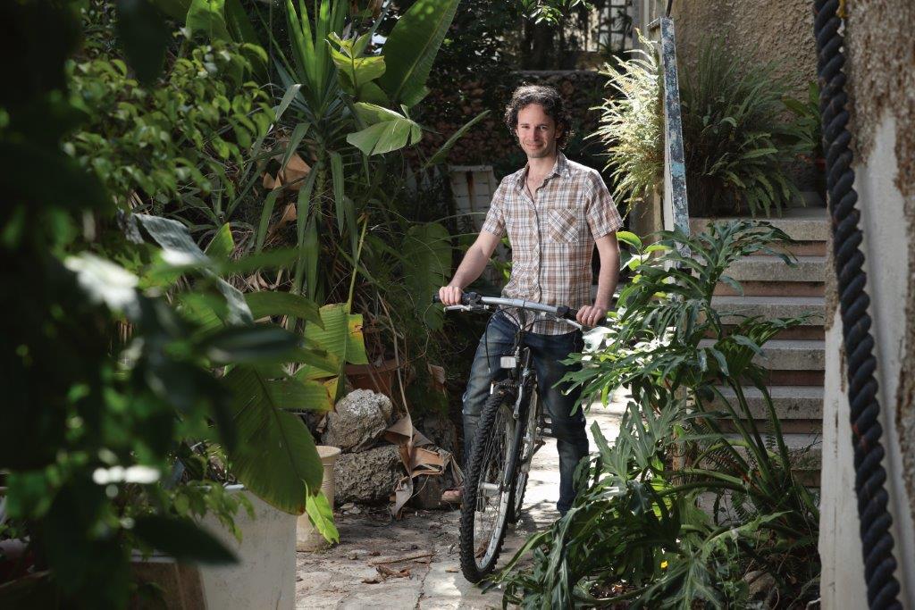 Itay Remer, an Azrieli Graduate Studies Fellow, rides a bike through foliage.