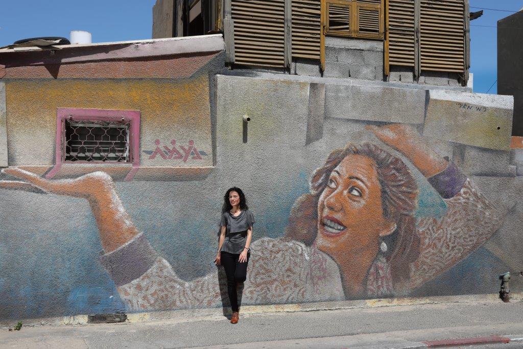 Meytal Nasie, an Azrieli Graduate Studies Fellow, leans against a mural.