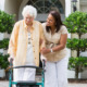 A caregiver assisting a person with a walker.