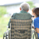 A caregiver sitting outside with a person in a wheelchair.