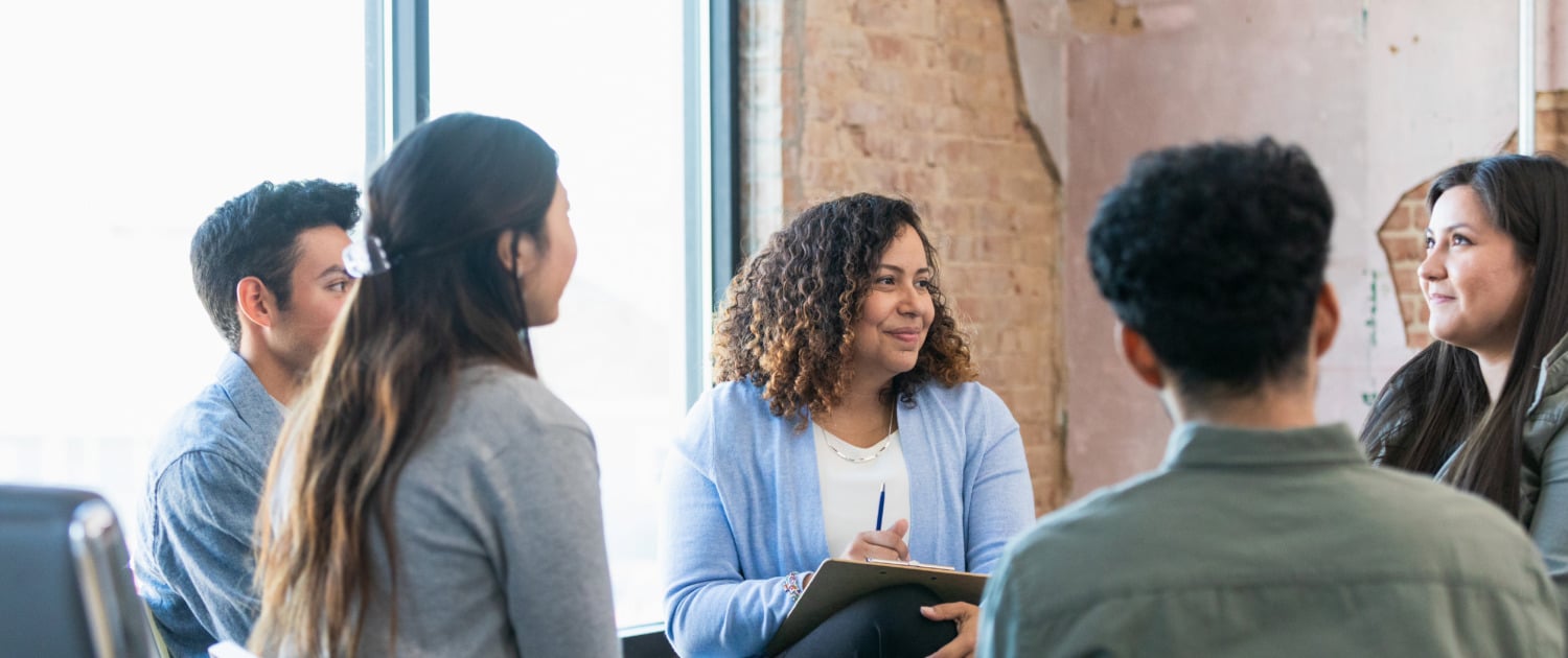 Therapy group listens attentively as young woman shares The diverse therapy group listens attentively as the young adult woman shares.