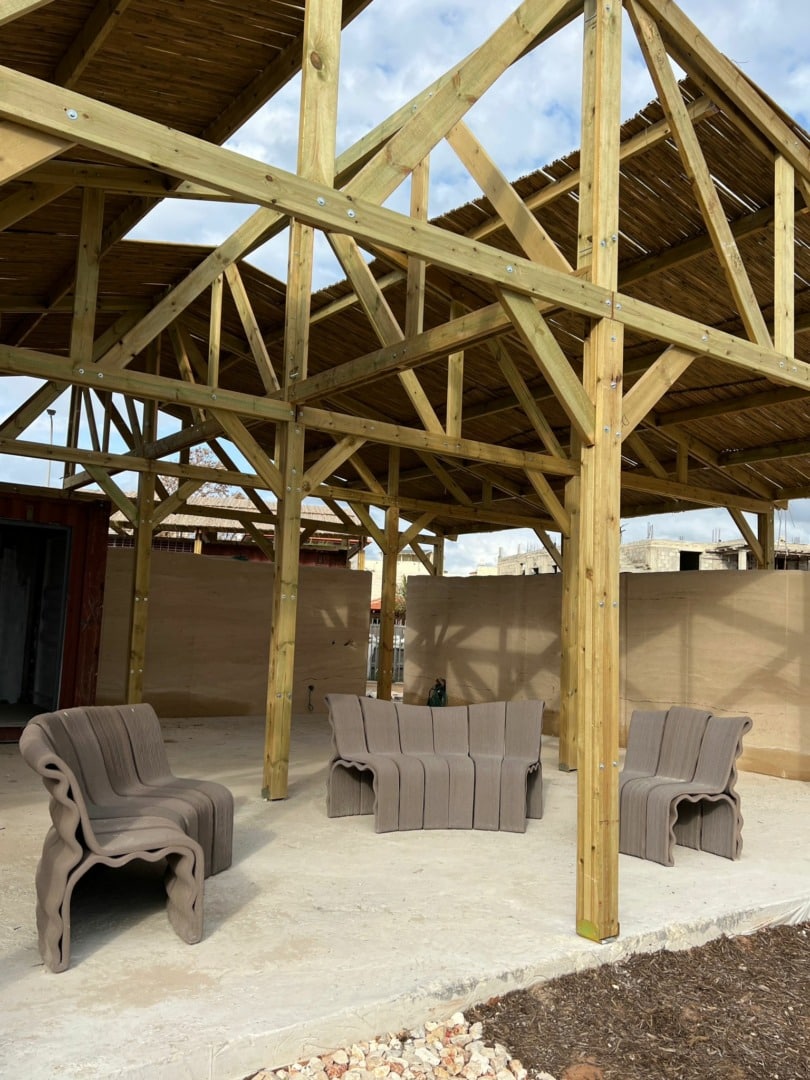 Three benches underneath a partially built outdoor structure.