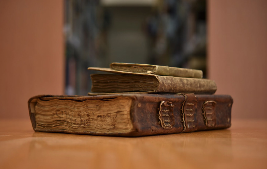 Three old, leather-bound books sitting on top of a table.
