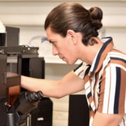 A person wearing a striped shirt adjusts a microscope.