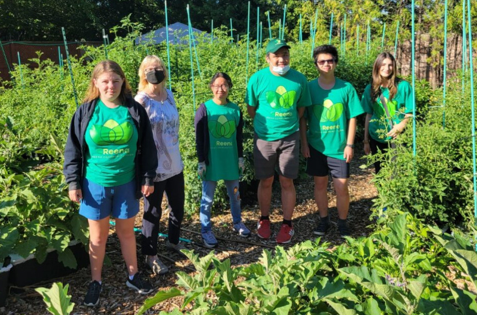 Six individuals standing in a very green garden wearing green tshirts.