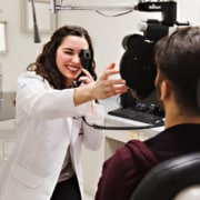 An optometrist using their instruments to check a patient's eyes.
