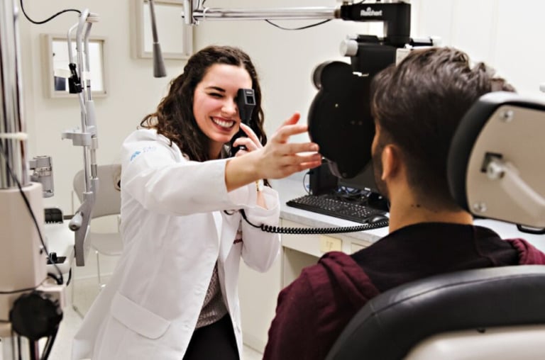 An optometrist using their instruments to check a patient's eyes.
