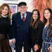 An older adult in a suit and tie poses for a photo with three other adults.