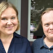 Two individuals with dark blue shirts smiling for a photo.