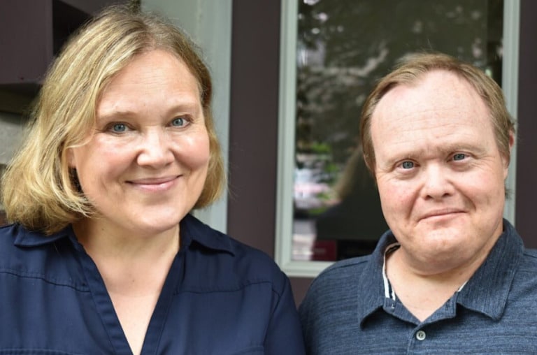 Two individuals with dark blue shirts smiling for a photo.