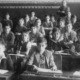 A black and white photo of young students at their desks in a crowded classroom.