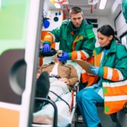 Two emergency response workers in the back of an ambulance with a patient.